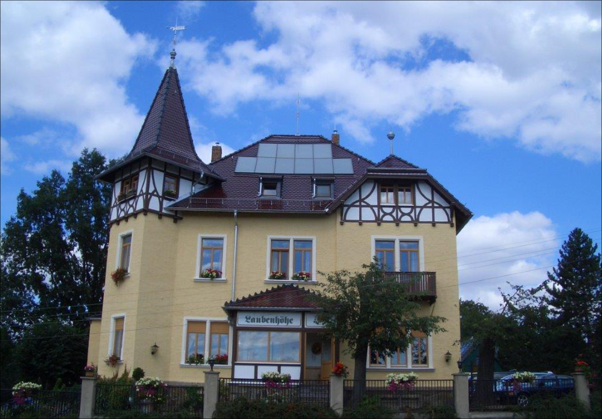 Gelbes Gebäude mit markantem Dachturm und Solaranlage