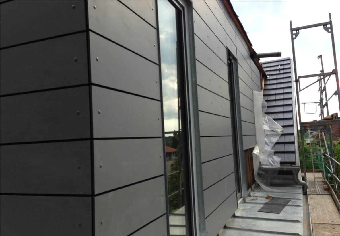 Fassade mit grauen Verkleidungselementen und schrägem Dachabschluss