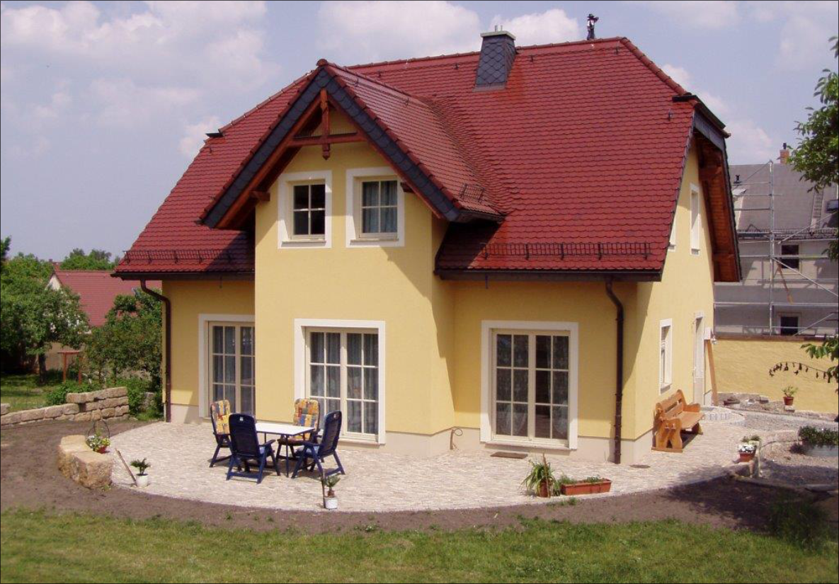 Fertige Wohnhausfassade mit rotem Schrägdach und Terrasse