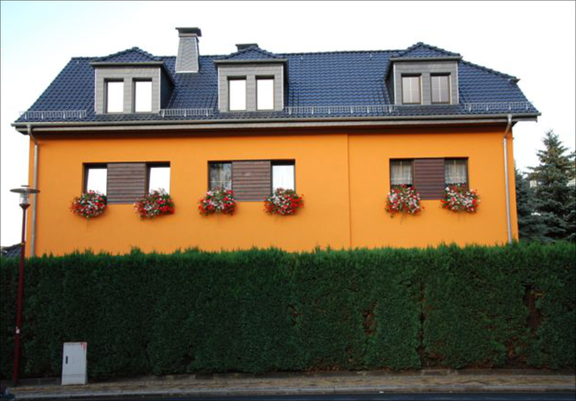 Orangefarbenes Wohnhaus mit blauer Dachdeckung und Dachgauben